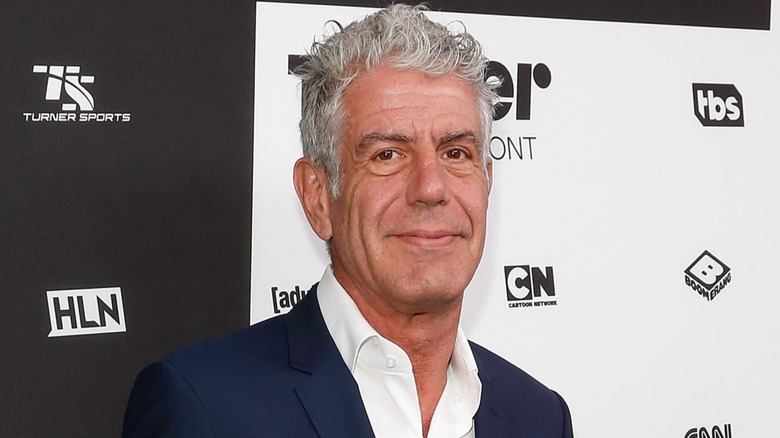 Anthony Bourdain in suit at press event.