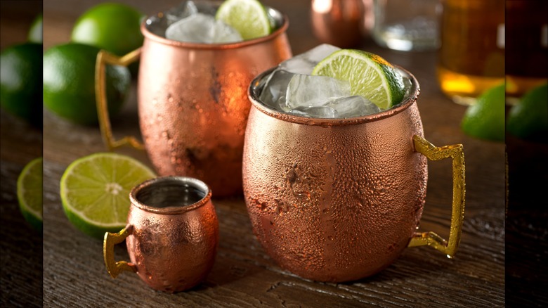 Two Moscow mule cocktails in chilled glasses with ice and a lime garnish.