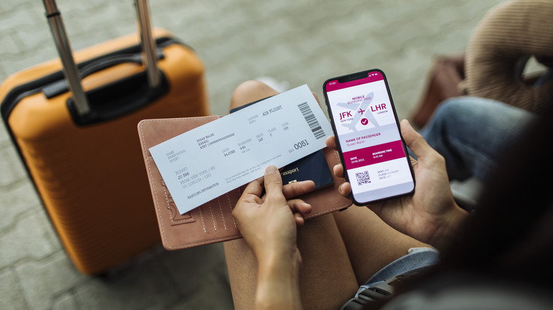 person holding airline ticket and checking flight reservation on smartphone