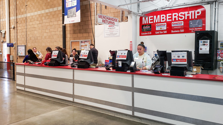 The merchandise returns section of a membership counter at Costco with workers standing behind registers