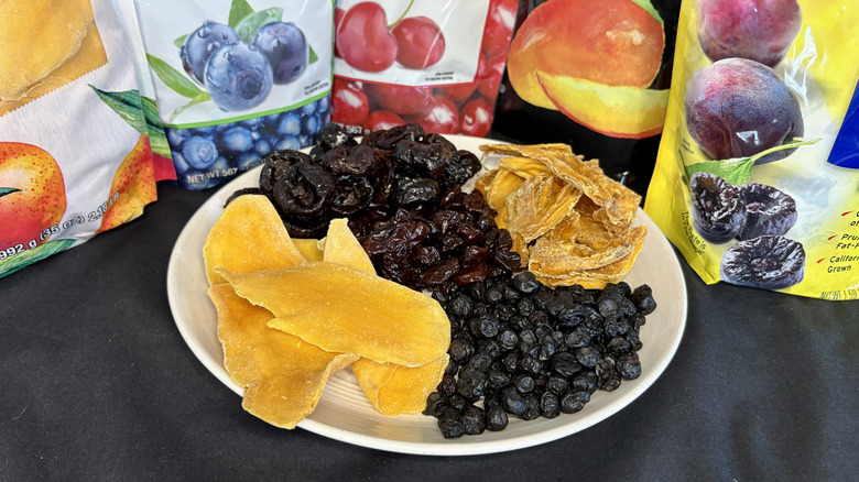 A variety of dried fruits on a plate surrounded by the fruits' packaging