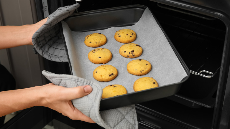 Cookies being put in the oven on a baking sheet.
