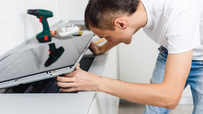 Young person installing an induction stovetop