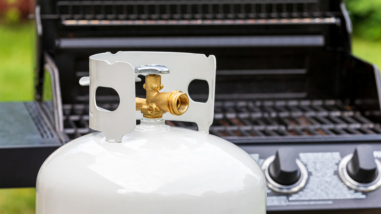 Closeup of propane tank with grill in background