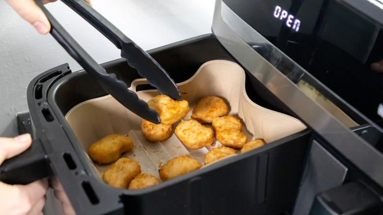 Chicken nuggets cooking in a black plastic air fryer