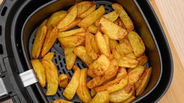 Overhead view of crispy potato wedges in a black air fryer coated with nonstick coating