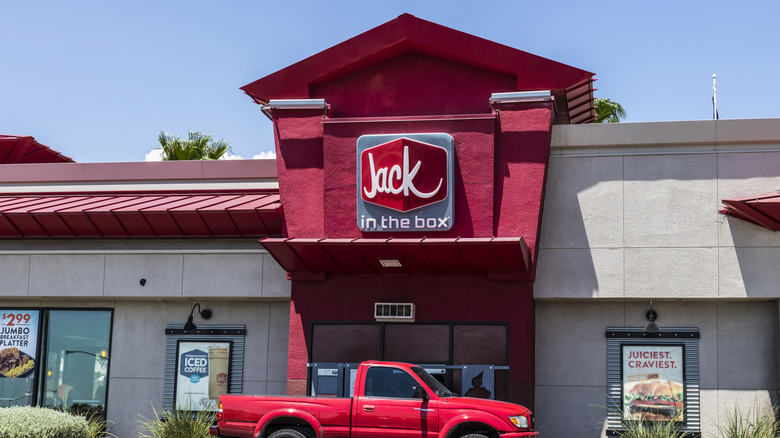 A red pickup truck at a drive-thru outside a Jack in the Box restaurant