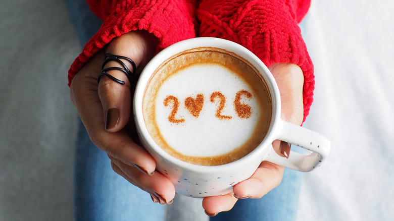 person holding coffee cup with 2026 written in the foam