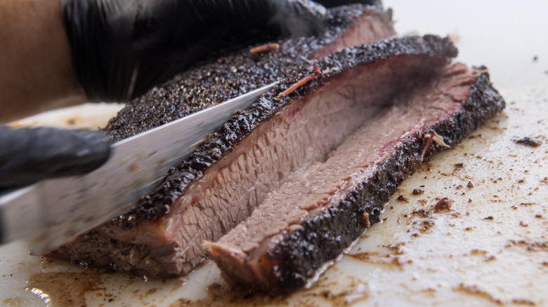 Slicing smoked brisket on a plastic cutting board