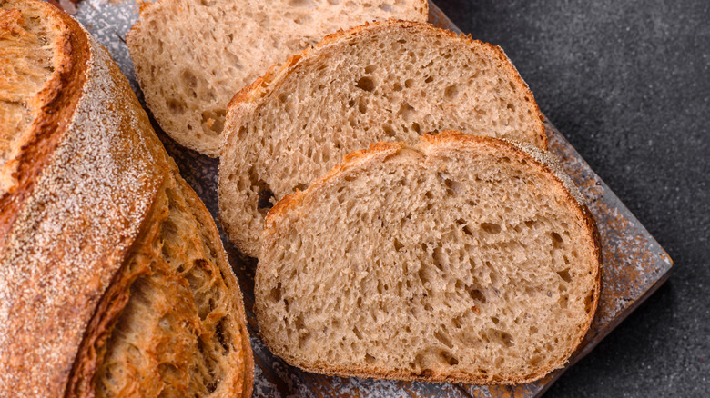 Two slices of rye bread next to a loaf