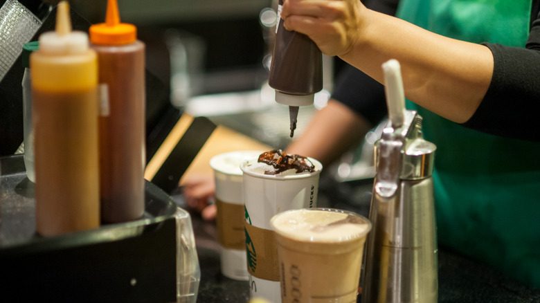 Starbucks employee adding chocolate syrup to drink