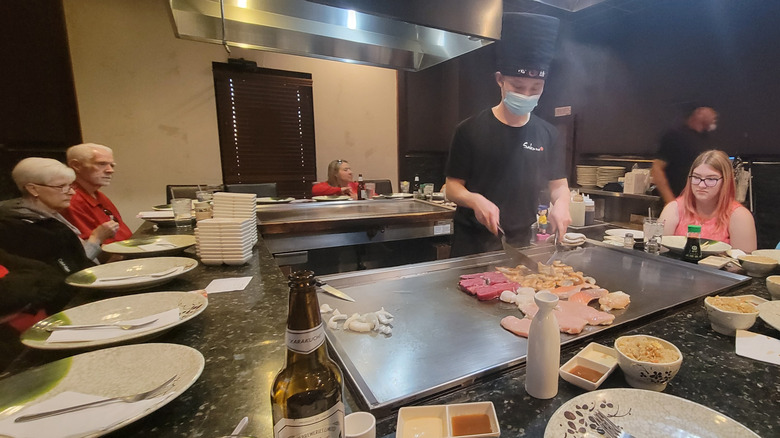 Diners sitting around a teppanyaki grill while the chef cooks