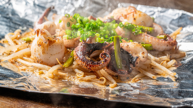 Steaming octopus with chow mein on top of foil