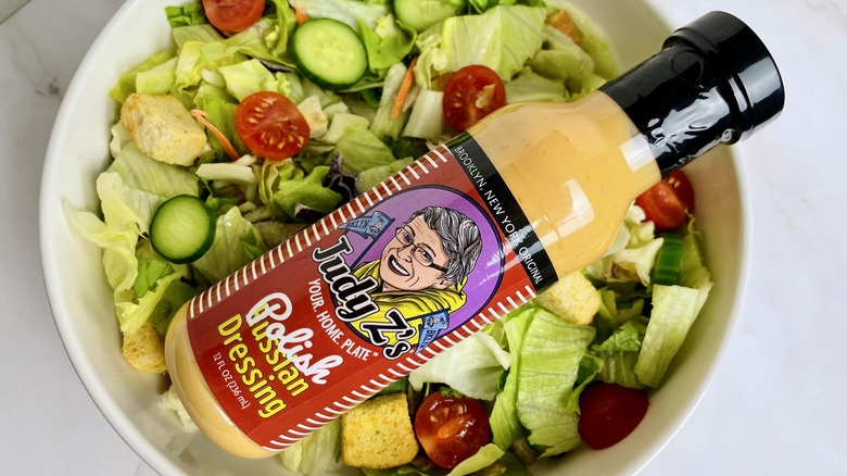 A bottle of Judy Z's Polish Russian Dressing sitting in a bowl of salad
