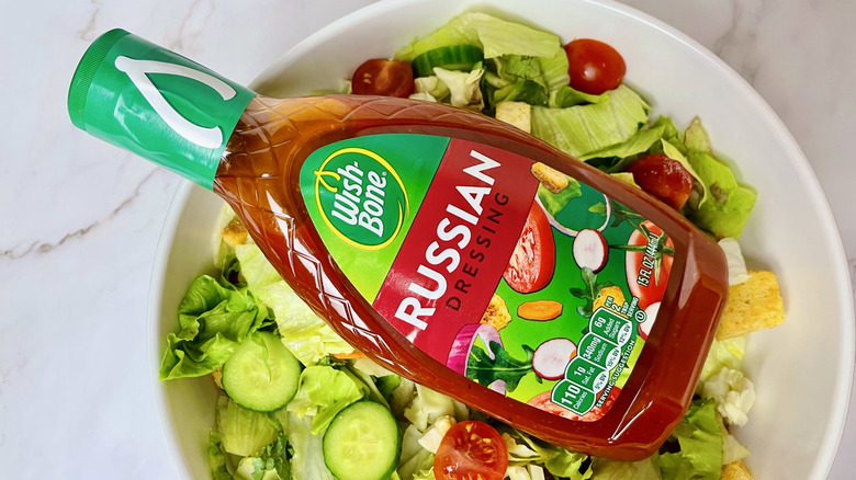 A bottle of Wish-Bone Russian Dressing sitting in a bowl of salad