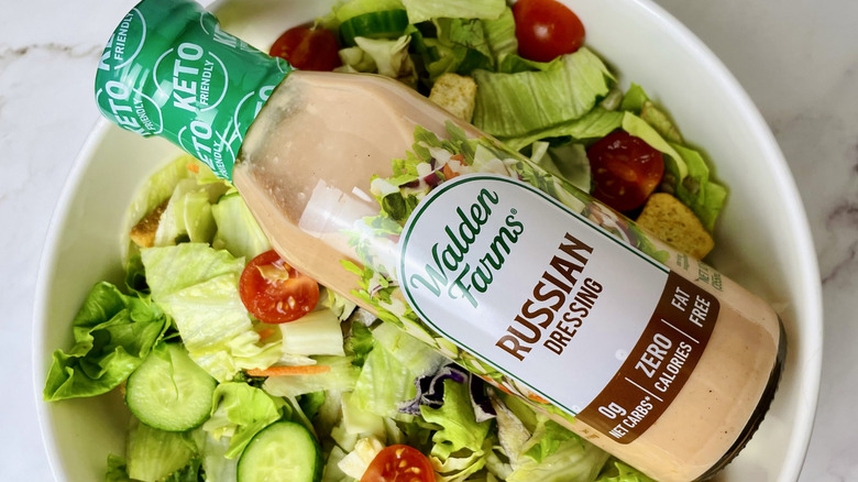 A bottle of Walden Farms Russian Dressing sitting in a bowl of salad