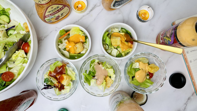 Several small bowls of salad, each topped with a different Russian salad dressing