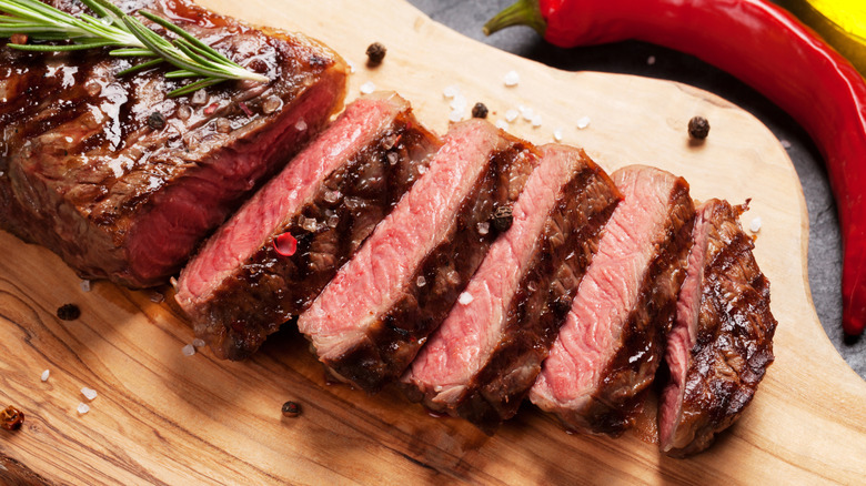 A sliced-up strip steak on a chopping board.