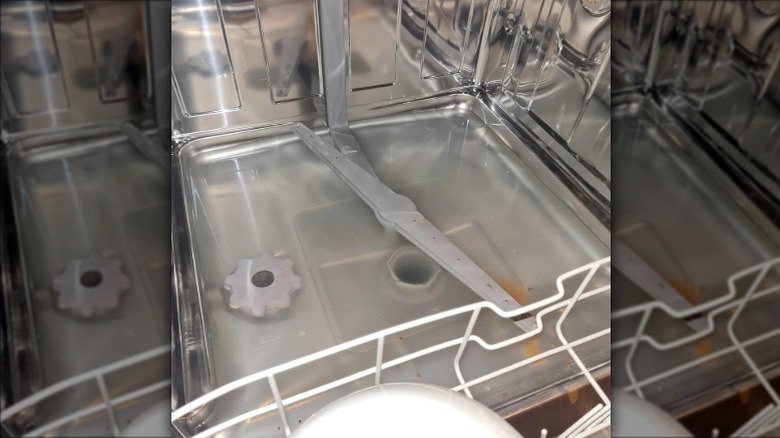 Dishwasher interior with water pooling at the bottom.