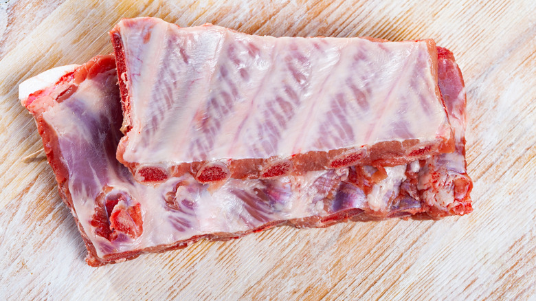 The underside of a rack of pork ribs showing the membrane