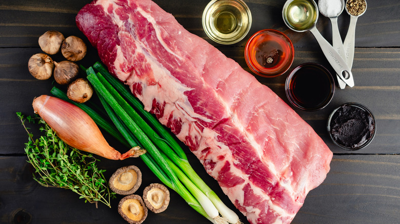 A rack of baby back ribs with assorted seasonings and sauces surrounding it on a wooden surface