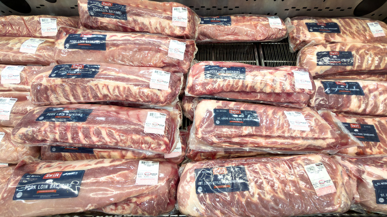 Multiple packages of pork ribs on display inside a supermarket