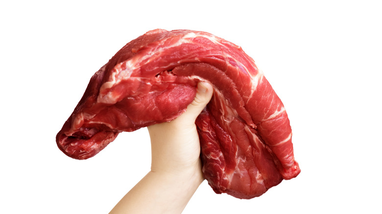 Hand holding up piece of meat that's flexing at both ends