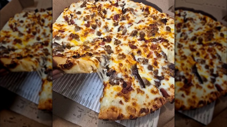 A Domino's pizza with cheddar cheese, bacon, and Philly beef steak on top