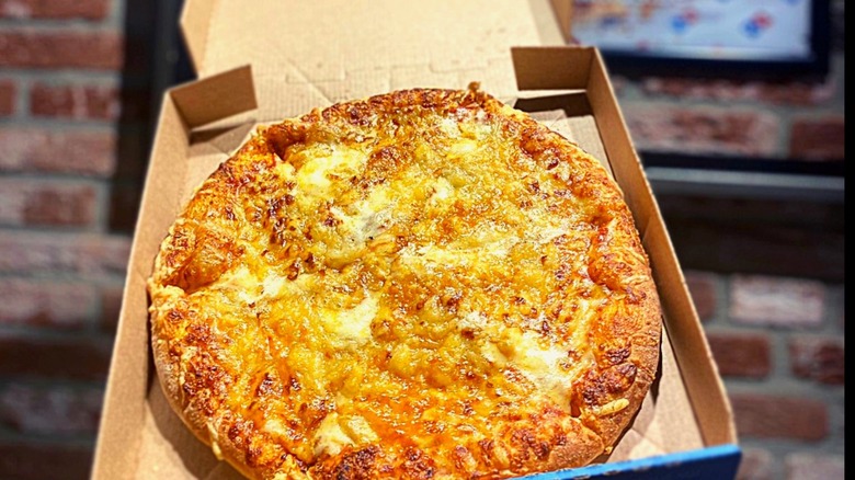 An open Domino's pizza box with an ultimate 5 cheese lava pizza