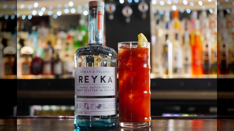 Bottle of Reyka vodka on bar next to Bloody Mary cocktail