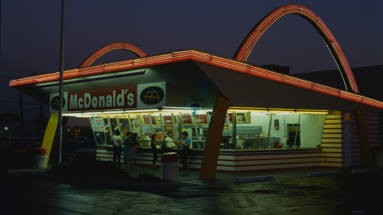 A historical McDonald's restaurant with neon lights and a large service window at night
