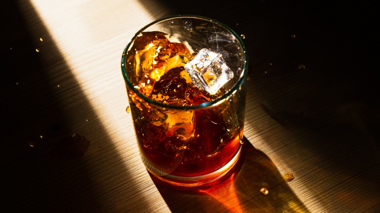 A glass of bourbon sitting on a table