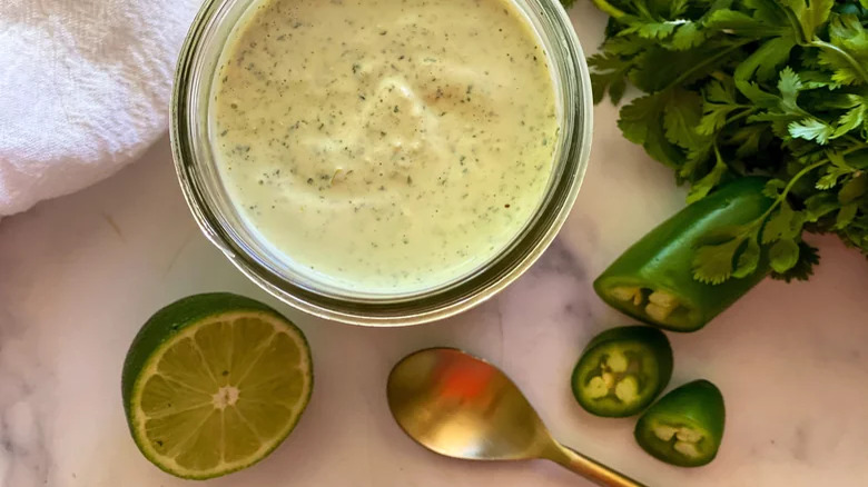 bowl of Copycat Chuy's Creamy Jalapeño Dip with limes and cilantro