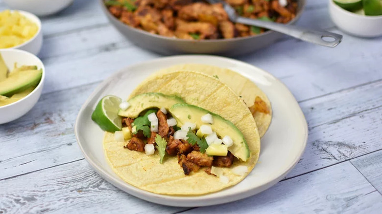 Soft tortillas with pork, avocado, and diced onion.