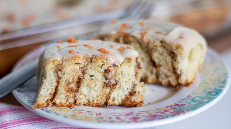 Iced cinnamon roll cut in half on a plate.