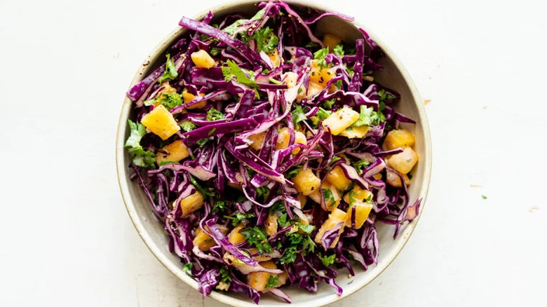 Bowl of slaw with purple cabbage and pineapple.