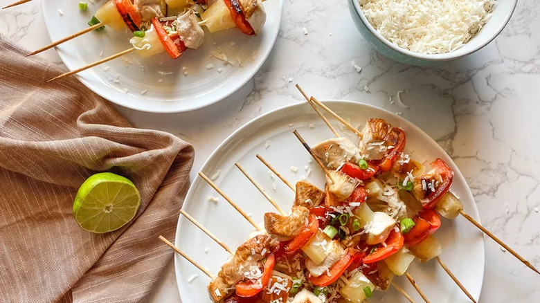 Chicken, pineapple, and vegetable skewers on plates.