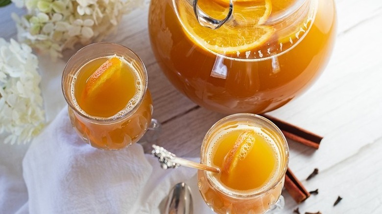 Pitcher and glasses with mulled tea and orange slices.