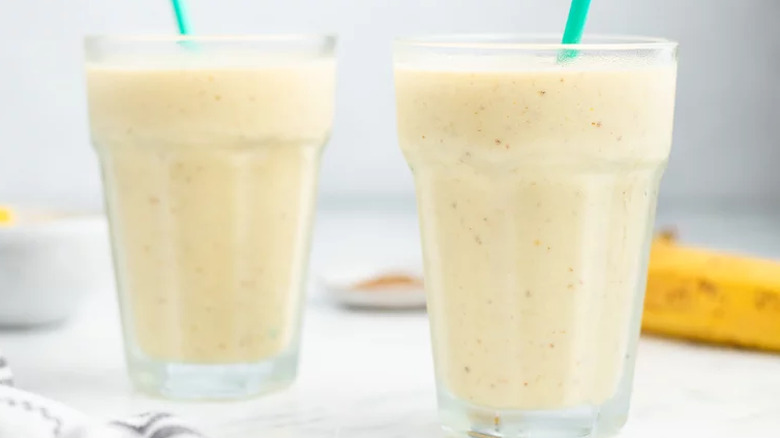 Two tall glasses with thick smoothies and straws.