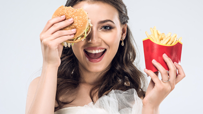 Woman in wedding dress with fast food