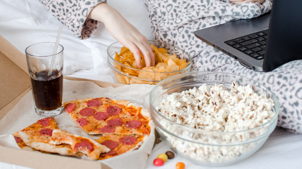 Movie snacks in bed with person in pajamas