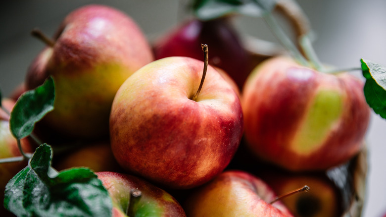 Closeup of fresh apples in a basket with green leaves