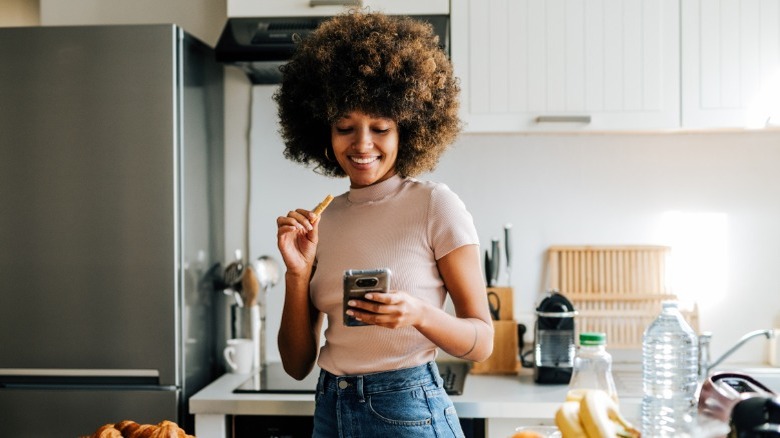 Person using smart phone near fridge