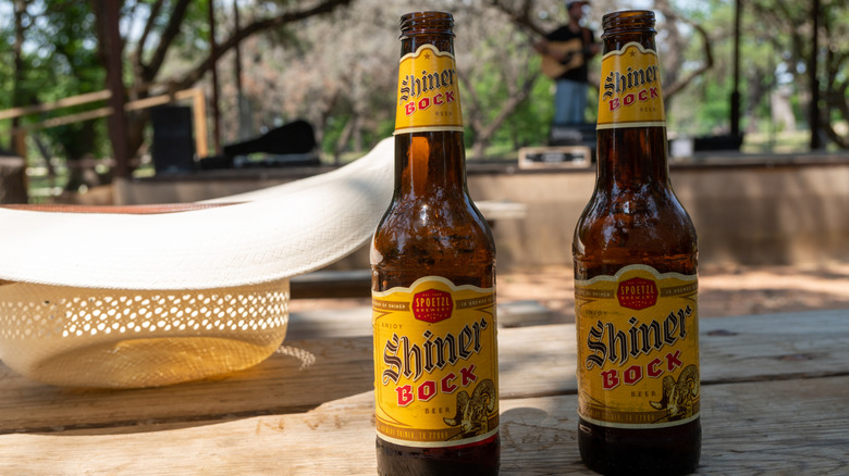 Bottles of Shiner Bock on a patio next to a straw hat