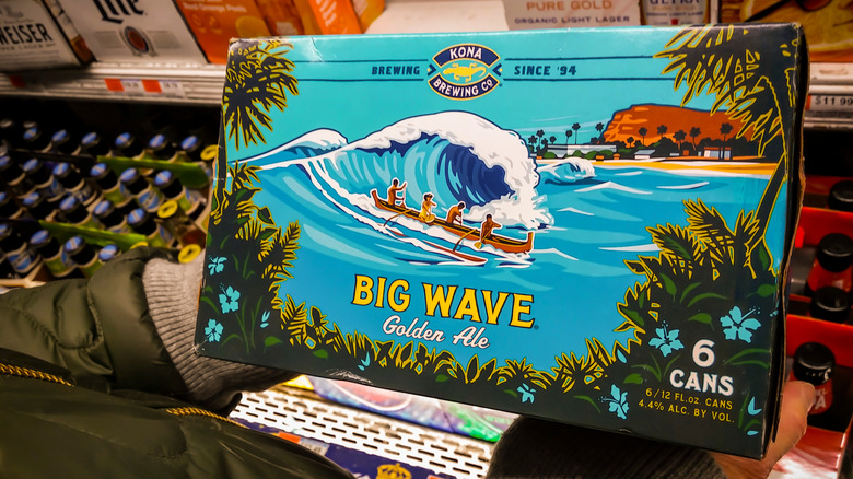 Person holding a six-pack of Kona Big Wave Golden Ale