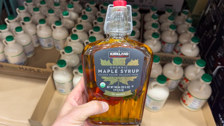 hand holding a glass bottle of organic golden maple syrup at Costco