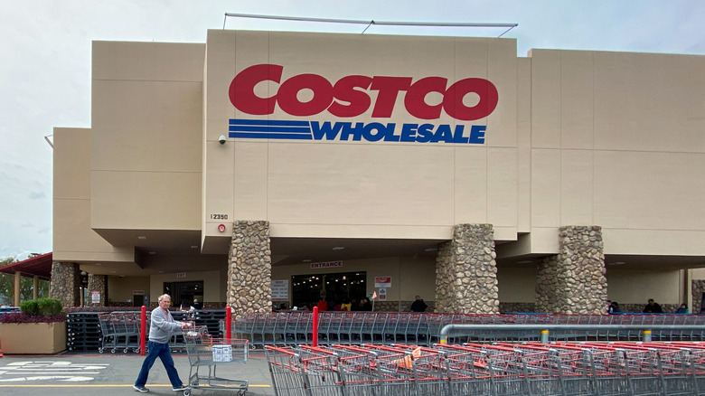 man pushing cart in front of Costco storefront