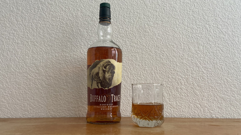 Buffalo Trace bourbon bottle beside half-full glass