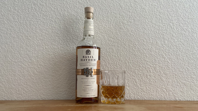Basil Hayden bourbon bottle beside half-full glass