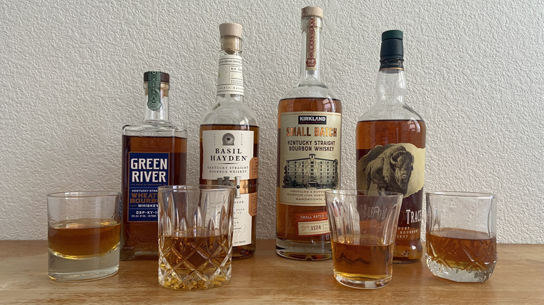 Four bourbon bottle's beside four half-full glasses
